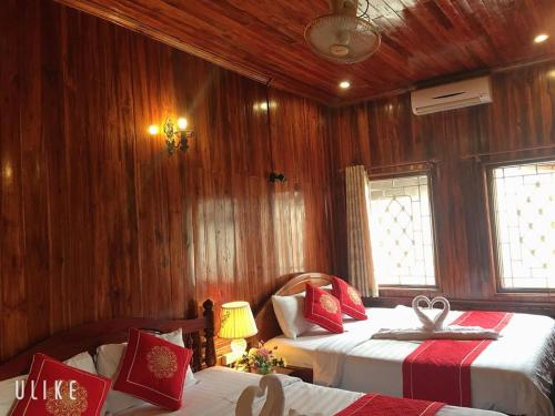 um quarto com 2 camas e paredes com painéis de madeira em Soutikone Place House 2 em Luang Prabang