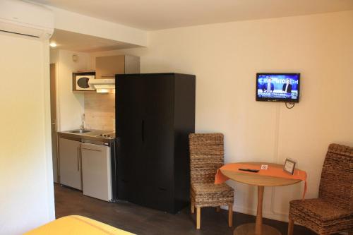 a small room with a small table and a kitchen at Logis Hôtels Le Saint Marc in Mollans-sur-Ouvèze