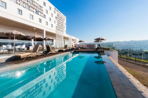 a swimming pool with chairs and umbrellas next to a building at Onomo Hotel Kigali in Kigali