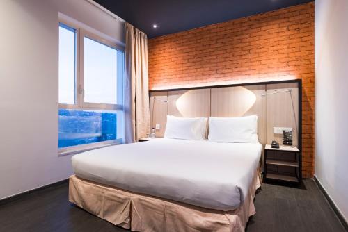 キガリにあるOnomo Hotel Kigaliのレンガの壁、大きなベッド付きのベッドルーム1室