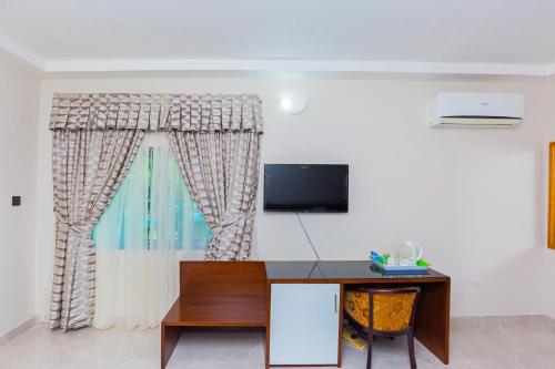a room with a desk and a television on a wall at Monarch Hotel in Accra