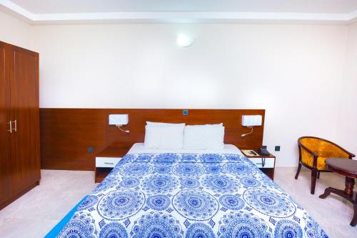 a bedroom with a bed with a blue and white bedspread at Monarch Hotel in Accra