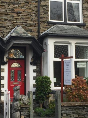 a red door on a house with a sign in front at Westbury House in Windermere