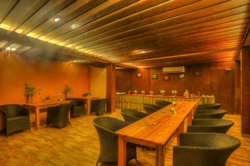 a restaurant with a long wooden table and chairs at The Hermitage Kanatal in Kanatal