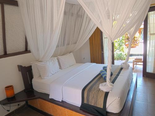 a bedroom with a bed with white curtains at Gili Air Bungalows in Gili Air
