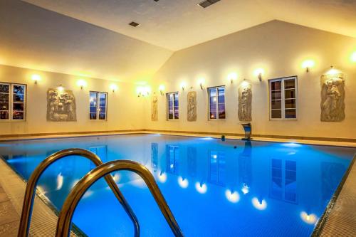 a large swimming pool with blue water in a house at Hotel Sobienie Królewskie in Sobienie Szlacheckie