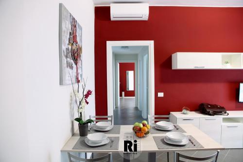 una cocina con paredes rojas y una mesa con fruta. en Residenze Italia en Sesto San Giovanni