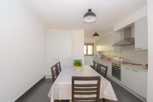 a white kitchen with a table and chairs in it at DUPLEX in Nazaré