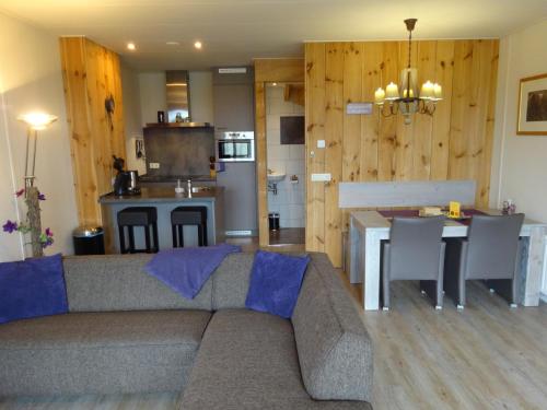 ein Wohnzimmer mit einem Sofa und einem Tisch sowie eine Küche in der Unterkunft Crea-Trends Vacations in Sluis