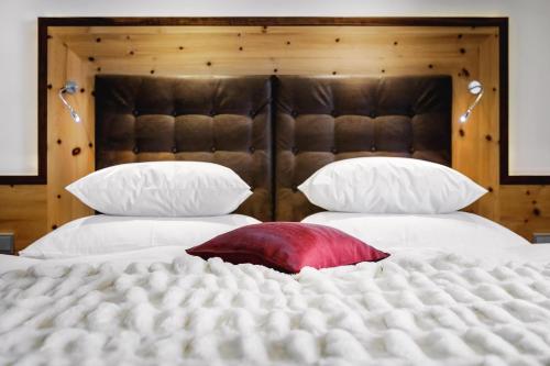 a large white bed with a red pillow on it at Alpinlounge Rätia Appartements in Ischgl