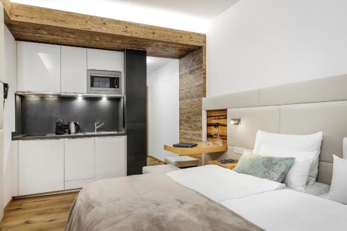 a bedroom with a white bed and a kitchen at Alpinlounge Rätia Appartements in Ischgl