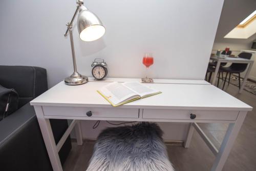 a white desk with a book and a lamp at LURIA apartmani - Self Check-in in Čakovec