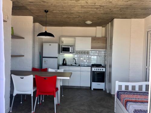 a kitchen with a table and red chairs in a room at Las Olas Aparts in La Paloma