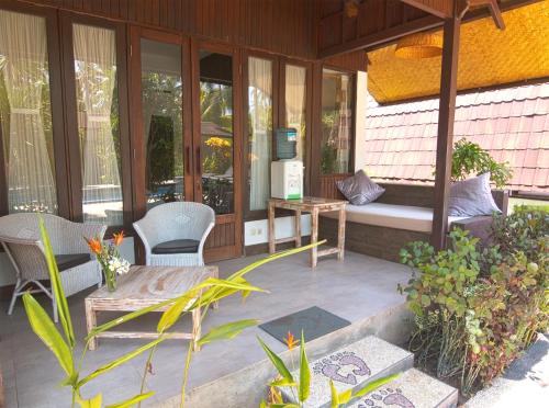 a screened in porch with chairs and a bench at Gili Air Bungalows in Gili Islands