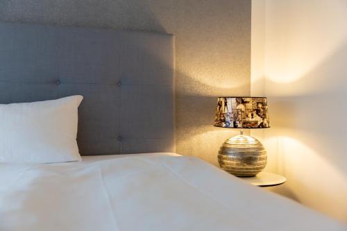 a bedroom with a white bed and a lamp at Parkhotel FRITZ am Brunnen in Schwelm