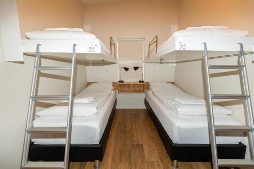 two bunk beds in a dorm room with white beds at Hrimland Cottages in Akureyri
