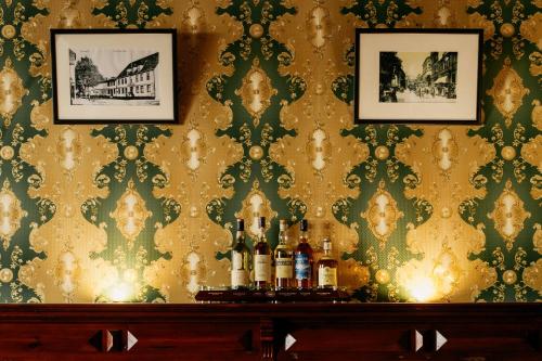 a bar with bottles of wine on a table with wallpaper at Hotel & Restaurant "Deutscher Kaiser" in Perleberg