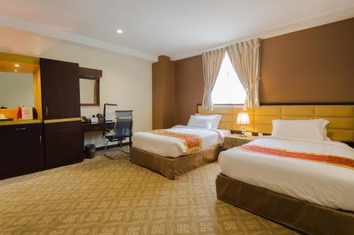 a hotel room with two beds and a desk at Hallmark Crown Hotel in Melaka