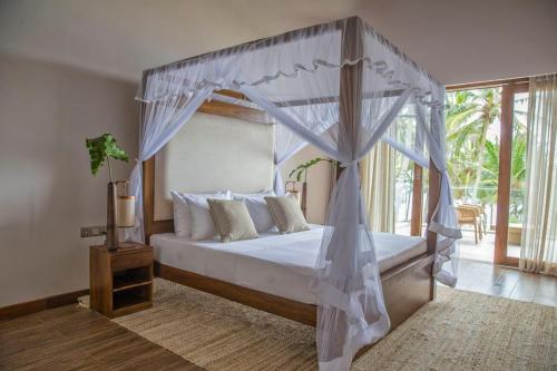 a bedroom with a bed with a canopy at Villa Blu in Tangalle