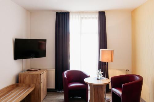 a hotel room with a tv and a table and chairs at Hotel & Restaurant "Deutscher Kaiser" in Perleberg
