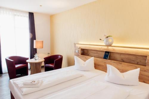 a hotel room with two beds and two chairs at Hotel & Restaurant "Deutscher Kaiser" in Perleberg
