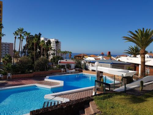 a swimming pool in a resort with palm trees at Style Apartment with Ocean view in Playa de las Americas