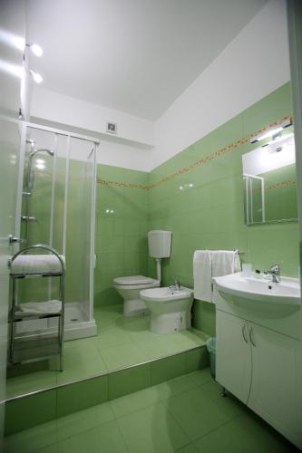 a green bathroom with a toilet and a sink at Arcobaleno Guest House Pellaro in Pellaro