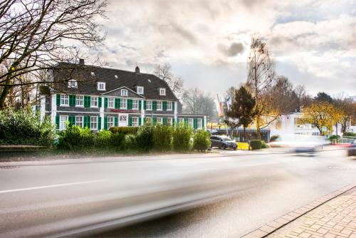 a house with green and white windows on a street at Parkhotel FRITZ am Brunnen in Schwelm
