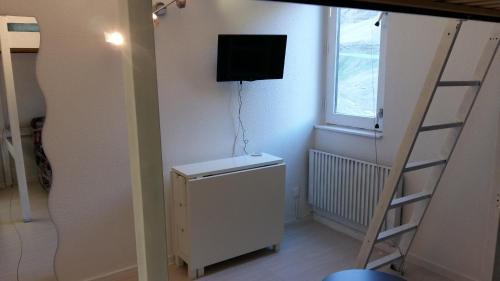 a room with a ladder and a television on the wall at Studio 4 personnes in La Mongie