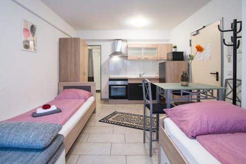 デュッセルドルフにあるDüsseldorf Comfort Apartmentのベッド2台、テーブル、キッチンが備わる客室です。