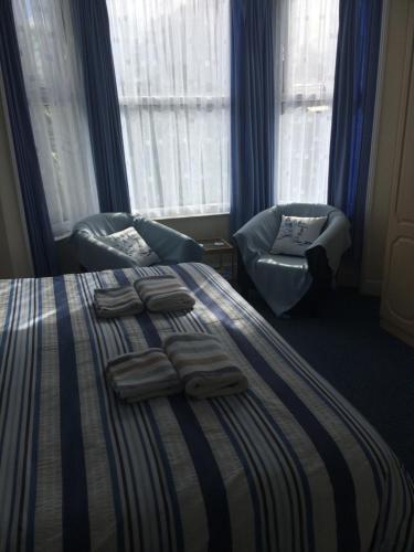 a bedroom with a bed with two chairs and towels on it at The Haldon Guest House in Paignton