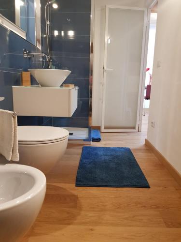 a bathroom with a toilet and a sink and a blue rug at Loft Bianco in Florence