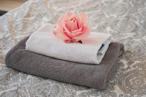 a pink rose sitting on top of towels on a bed at Düsseldorf Comfort Apartment in Düsseldorf