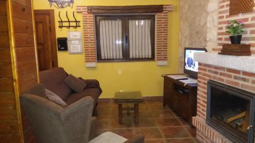 een woonkamer met een bank en een open haard bij Alameda II con CHIMENEA Salòn y BARBACOA en patio in Curiel de Duero