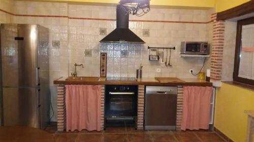 een keuken met een wastafel en een fornuis bij Alameda II con CHIMENEA Salòn y BARBACOA en patio in Curiel de Duero