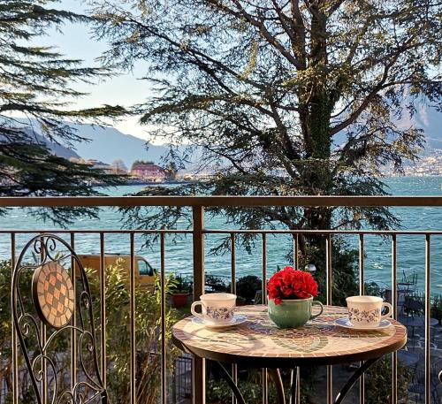 a table with two cups and a vase of flowers on a balcony at THE BEACH by Design Studio in Bellano