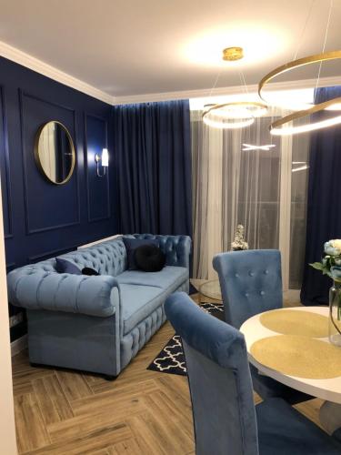 a living room with a blue couch and a table at Family & Business Sauna Apartments No2 Leśny nad Zalewem Cedzyna - 2 Bedroom with Private Sauna, Bath with Hydromassage, Terrace, Parking, Catering Options in Kielce
