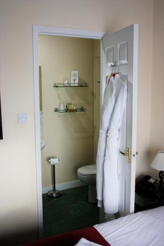 a bathroom with a toilet and a robe hanging on a door at Castle House Hotel in Canterbury