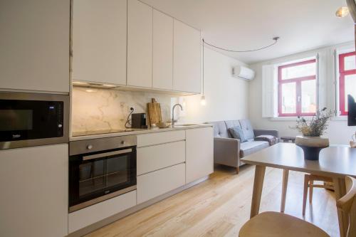 ポルトにあるOporto Sweet Home IVの白いキャビネットとテーブル付きのキッチンが備わります。