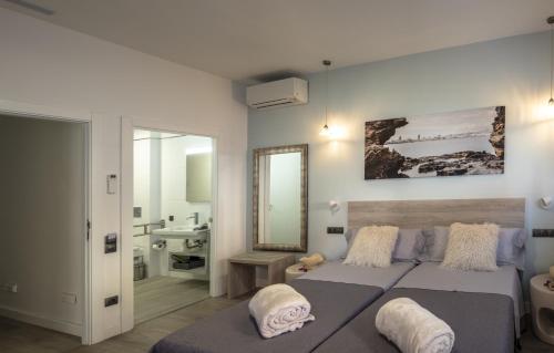 a bedroom with two beds and a sink and a mirror at La Palmera Hotel Boutique in Las Palmas de Gran Canaria