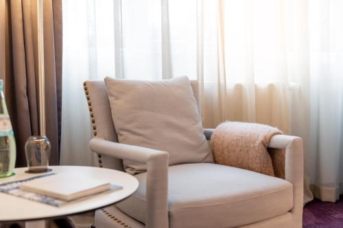 a living room with a chair and a table at Parkhotel FRITZ am Brunnen in Schwelm