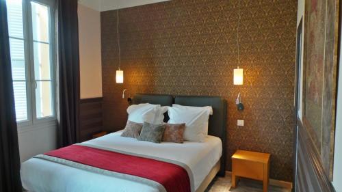 a bedroom with a large bed with a red blanket at Hotel Relais Du Postillon in Antibes