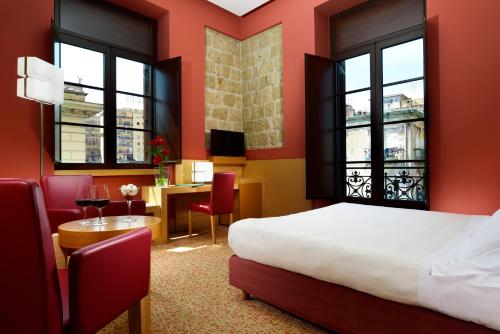 una camera d'albergo con letto, tavolo e sedie di UNAHOTELS Napoli a Napoli