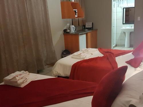 a hotel room with two beds with red sheets at Gemstone Guest House in Klerksdorp