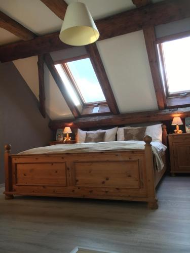 1 dormitorio con 1 cama grande de madera en el ático en B&B le Quinquet, en Les Bois