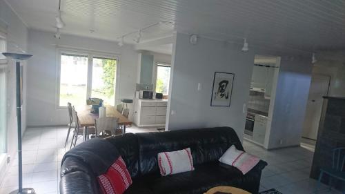 a living room with a leather couch and a table at Talvitaival Apartments in Varkaus