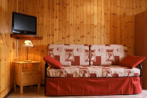 a room with a bed with a television on a wall at Case Vacanza Perron in Sauze dʼOulx