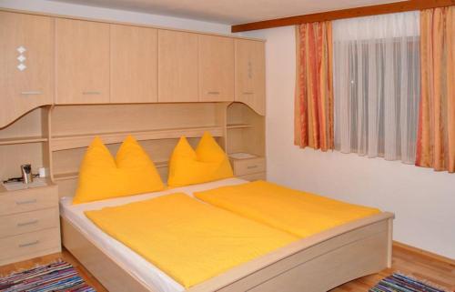 a bedroom with a large bed with yellow pillows at Appartementhaus Fuchs Christian in Westendorf
