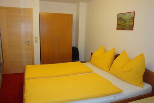 a yellow bed with yellow pillows in a bedroom at Appartementhaus Fuchs Christian in Westendorf