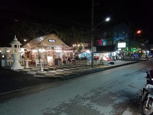 a night view of a street with a market with lights at Chatin Guesthouse in Khao Lak